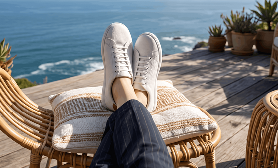 A person seated outdoors in a rattan chair wearing Birchbury Bramford leather sneakers